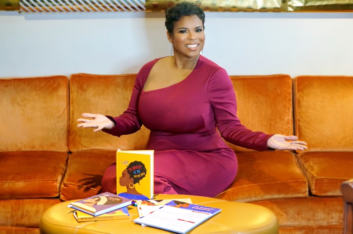Monica McCoy, founder of Authentically.Me, standing outdoors in a magenta gown holding her affirmation journal
